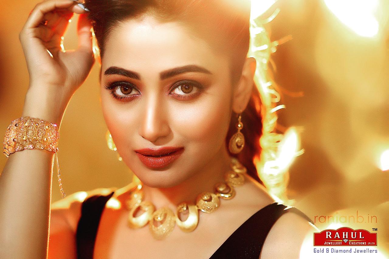 Elegant portrait of actress Sudipta Banerjee for Rahul Jewelers ad campaign by Ranjan Bhattacharya Photography. The actress is smiling while showcasing exquisite jewelry against a golden bokeh background.