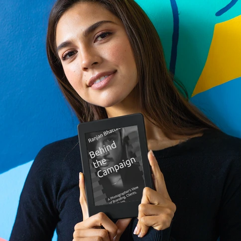 Real stories behind brand campaigns — from the lens of a photographer Woman holding 'Behind the Campaign' book by Ranjan Bhattacharya