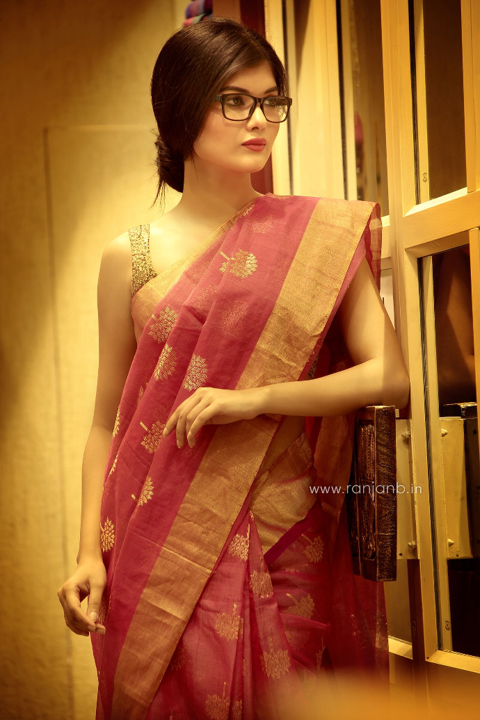 This captivating photograph showcases a woman in a pink sari, elegantly paired with glasses, embodying both tradition and modernity. A remarkable work from the portfolio of Roja Paromita Dey, beautifully executed by Ranjan Bhattacharya.