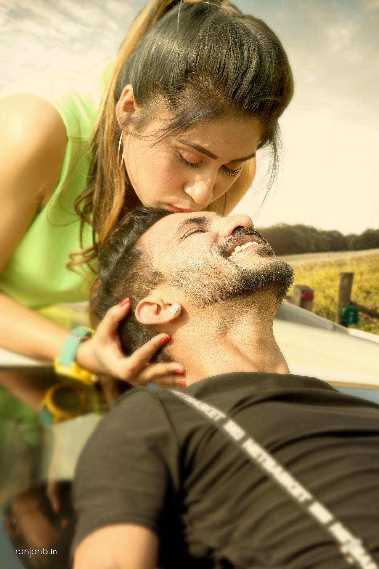 A close-up shot of a couple during their pre-wedding shoot, capturing their affectionate moment with the woman's arm around the man's neck and their faces close to each other.