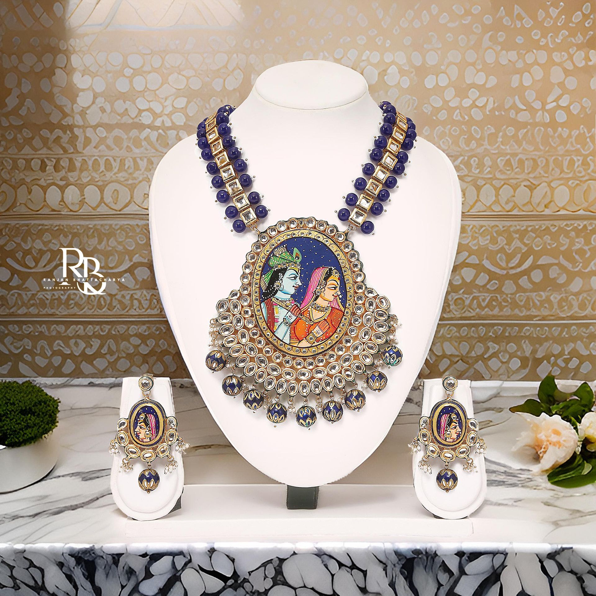 Handcrafted necklace and earrings set with Krishna & Radha Pichwai art and blue bead embellishments, photographed by Ranjan Bhattacharya.