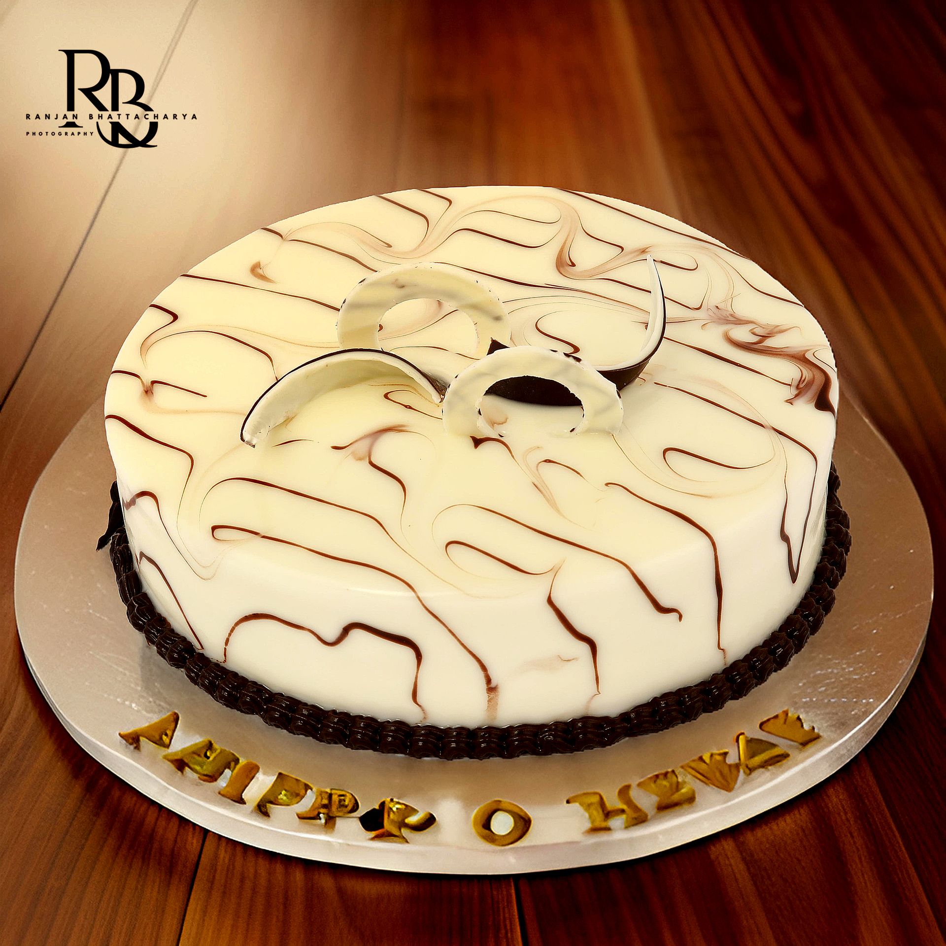 A white chocolate cake with artistic swirl designs and delicate white chocolate decorations on top, photographed by Ranjan Bhattacharya Photography for The Sugarr & Spice.