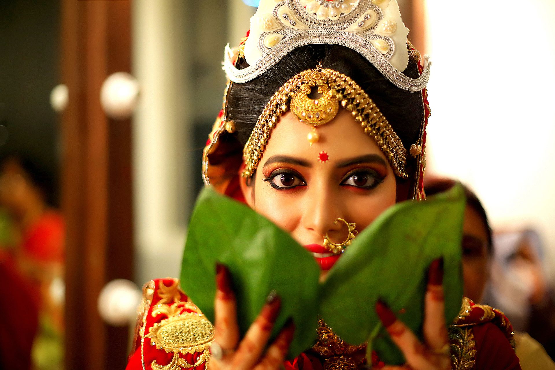 A beautiful woman in traditional Indian attire holds a leaf, captured candidly in a wedding portrait by Ranjan Bhattacharya.