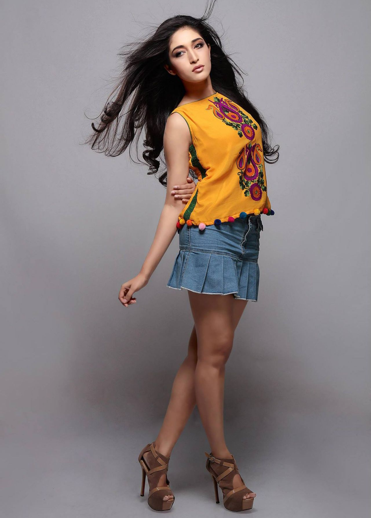 Stylish advertising photography featuring Mumbai model Madhura Dasgupta for Utsav Fashion. The model poses confidently in a vibrant yellow top and denim skirt, highlighting contemporary fashion trends.